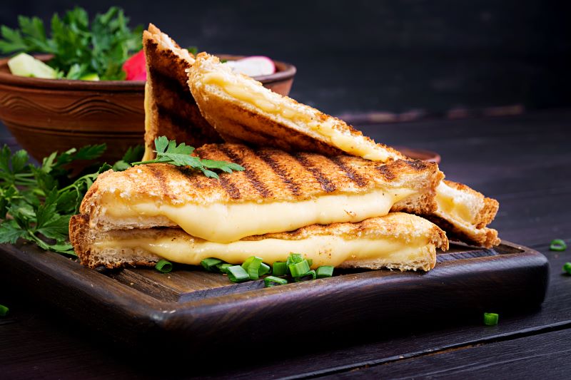 Two pieces of grilled cheese sandwich garnished with herbs