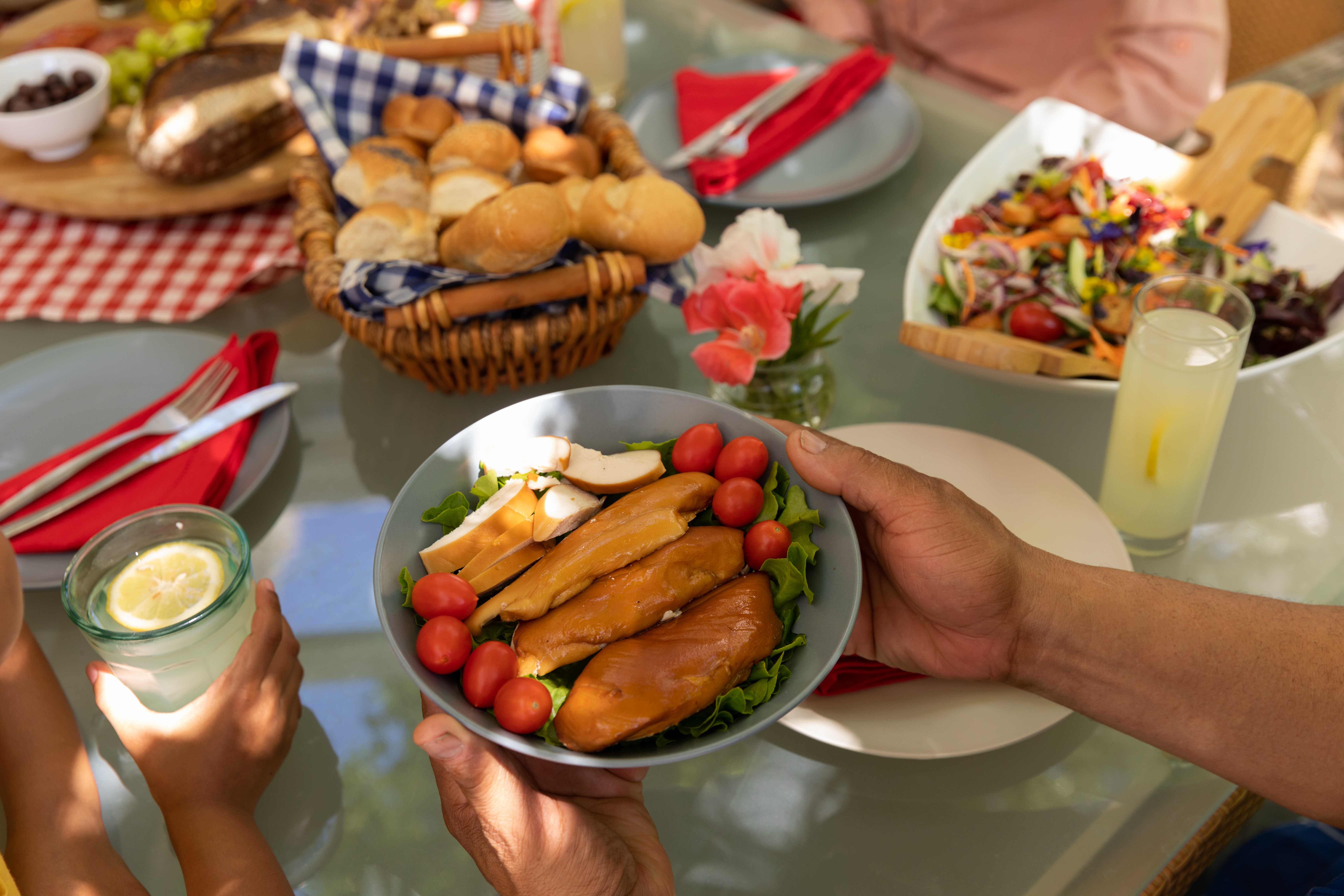 a table with foods and hands holding a bowl of bread and veggies