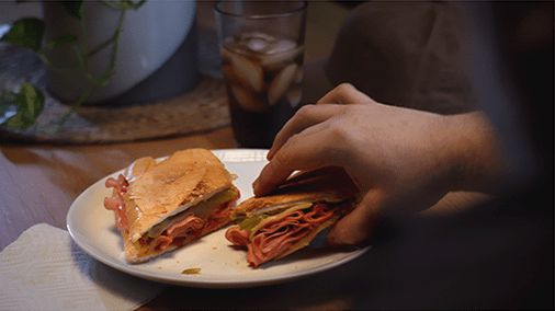 hand holding half of a ham sandwich