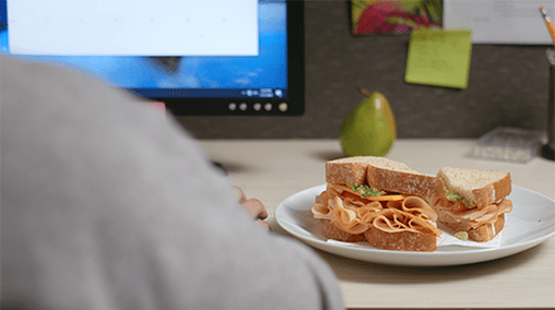 uneaten sandwich on a plate places on an office desk